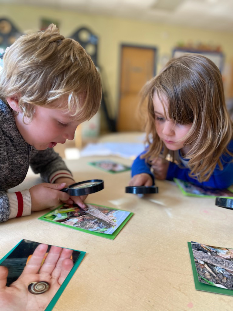 Kids looking at photos with magnifying glass