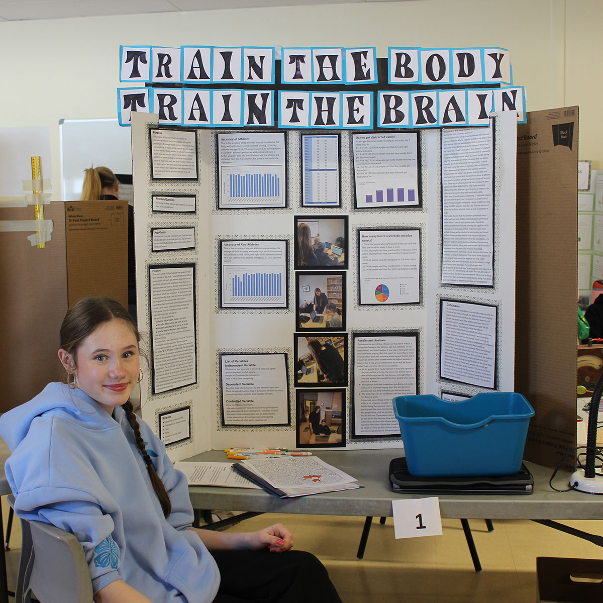At the HIS Junior High Science Fair, a student presents her research on the impact of physical training on focus and brain function.