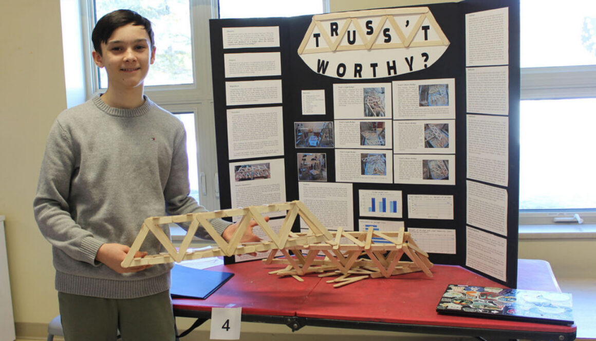 In preparation for the Halifax Sci-Tech Expo, a Jr High student presents his science fair research using a model and a tri-fold display.